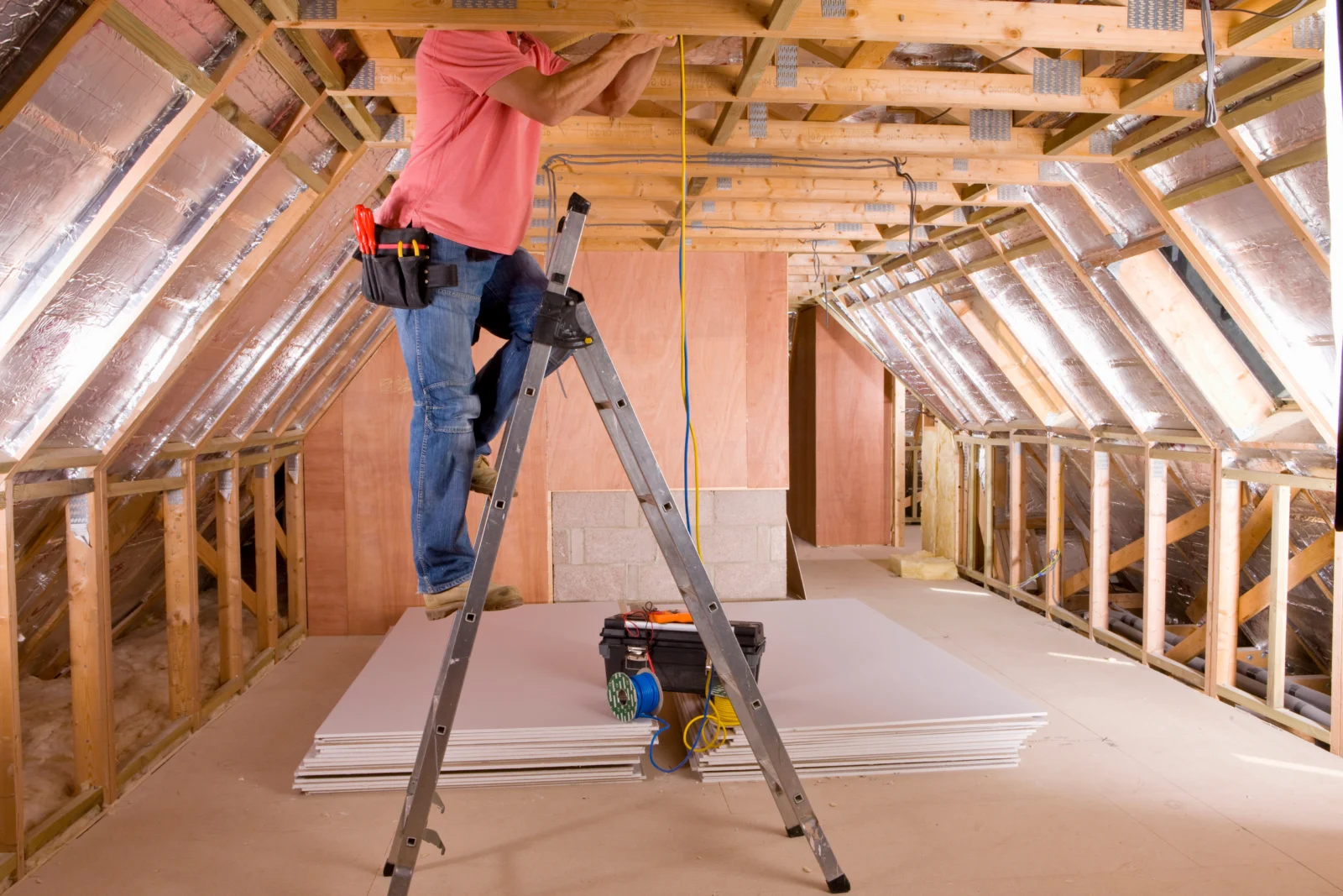 Handwerker arbeitet im Dachgeschoss unter den Dachsparren