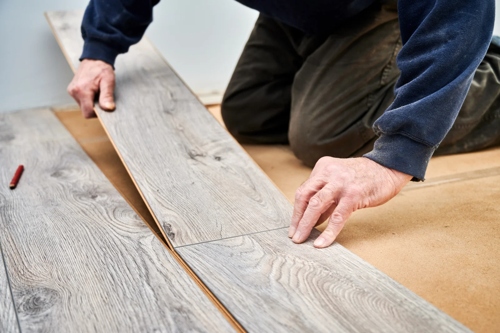 Handwerker verlegt Laminatdielen in Holzoptik