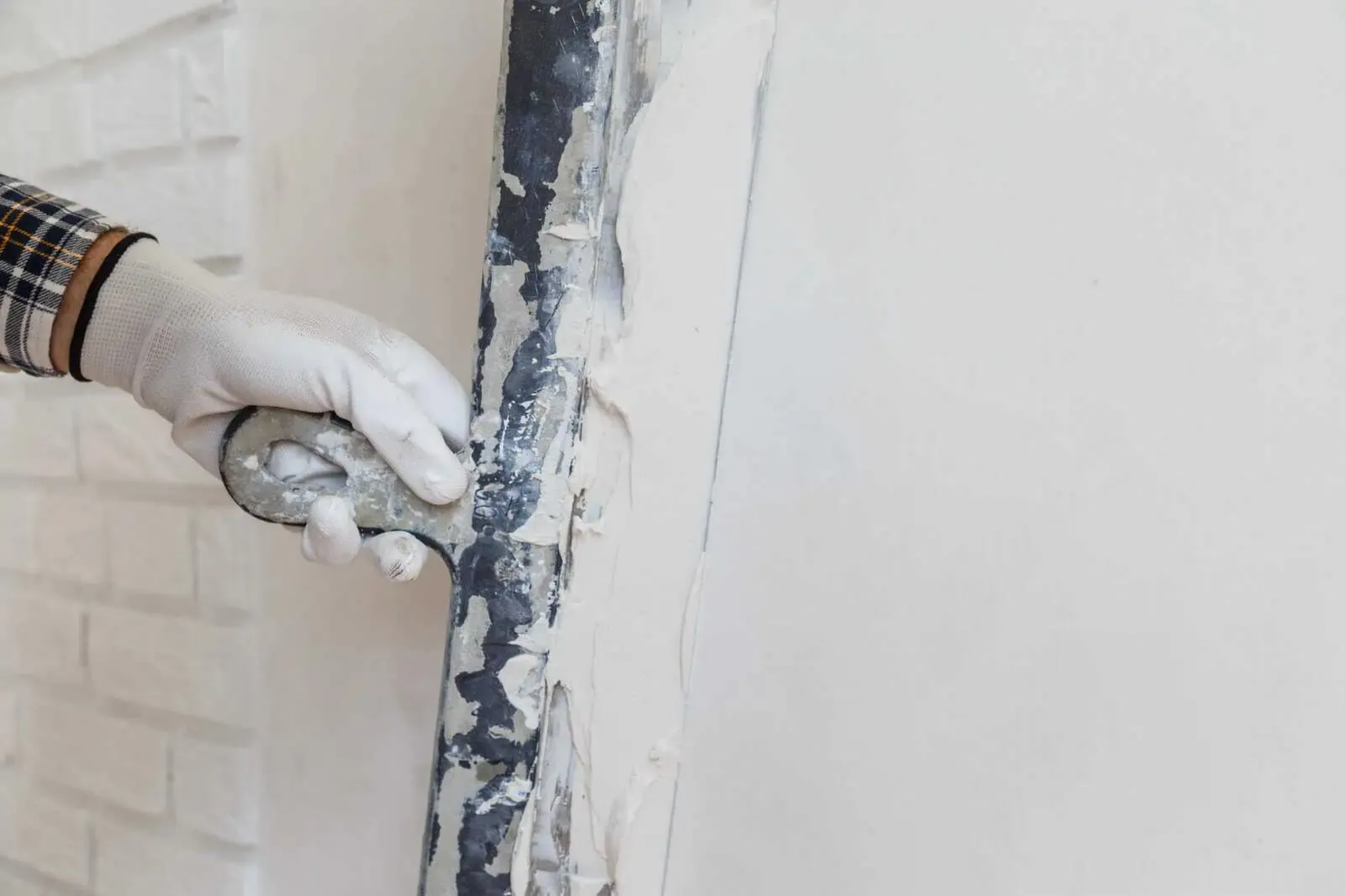 Handwerker glättet eine Wand mit dem Spachtel vor dem Anstrich