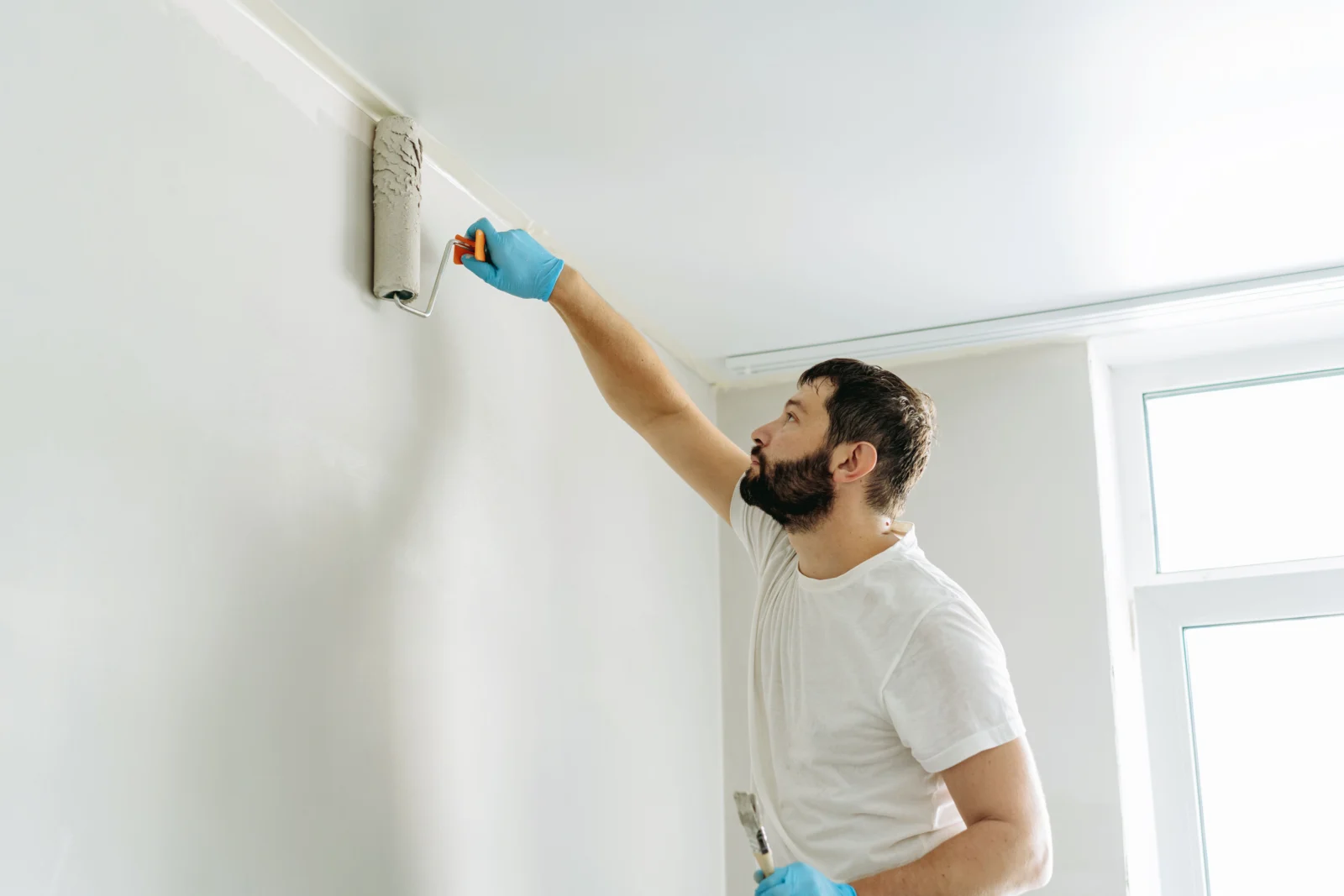 Maler streicht eine Innenwand mit der Farbrolle