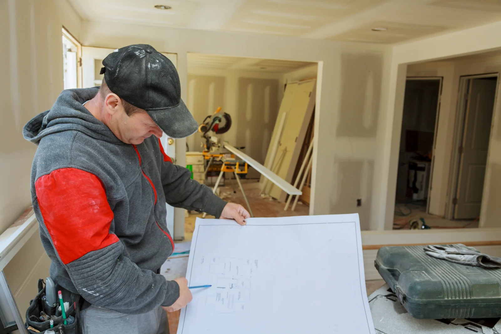 Handwerker prüft den Bauplan in einem Raum im Trockenbau